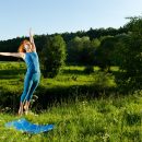 Leaping red haired woman practicing fitness yoga outdoors on a summer day