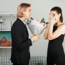 surprised young couple hugged each other on happy women day with bouquet girl whispers standing in living room